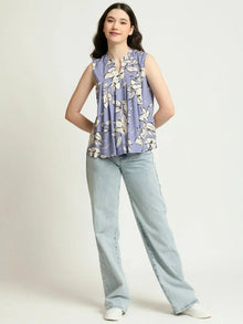 Woman wearing sleeveless floral top with light blue jeans and white sneakers