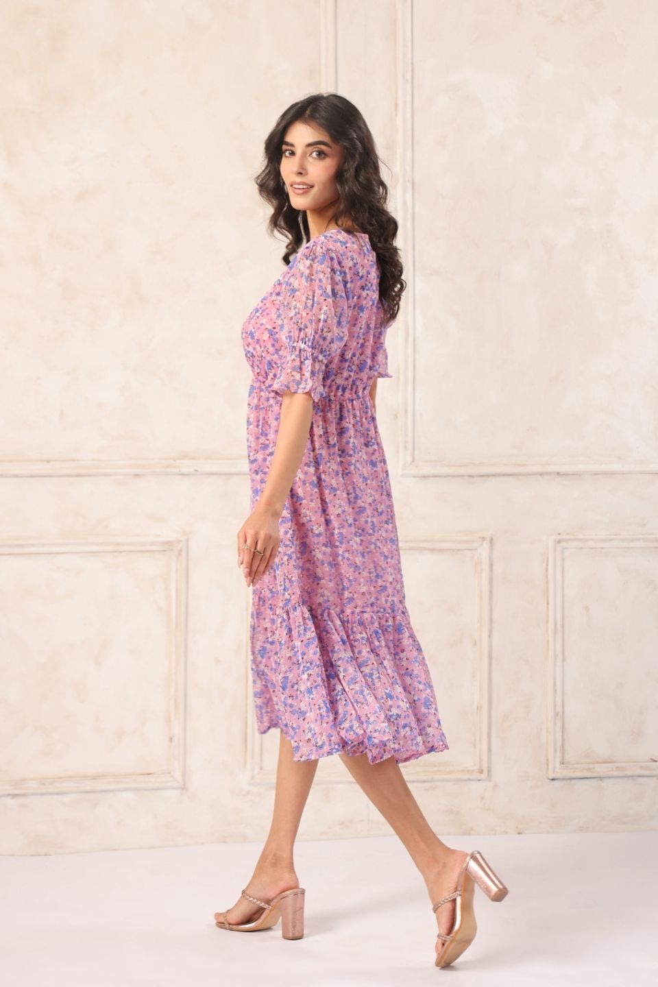 Woman in pink floral midi dress with puff sleeves, styled with gold heels for Western wear