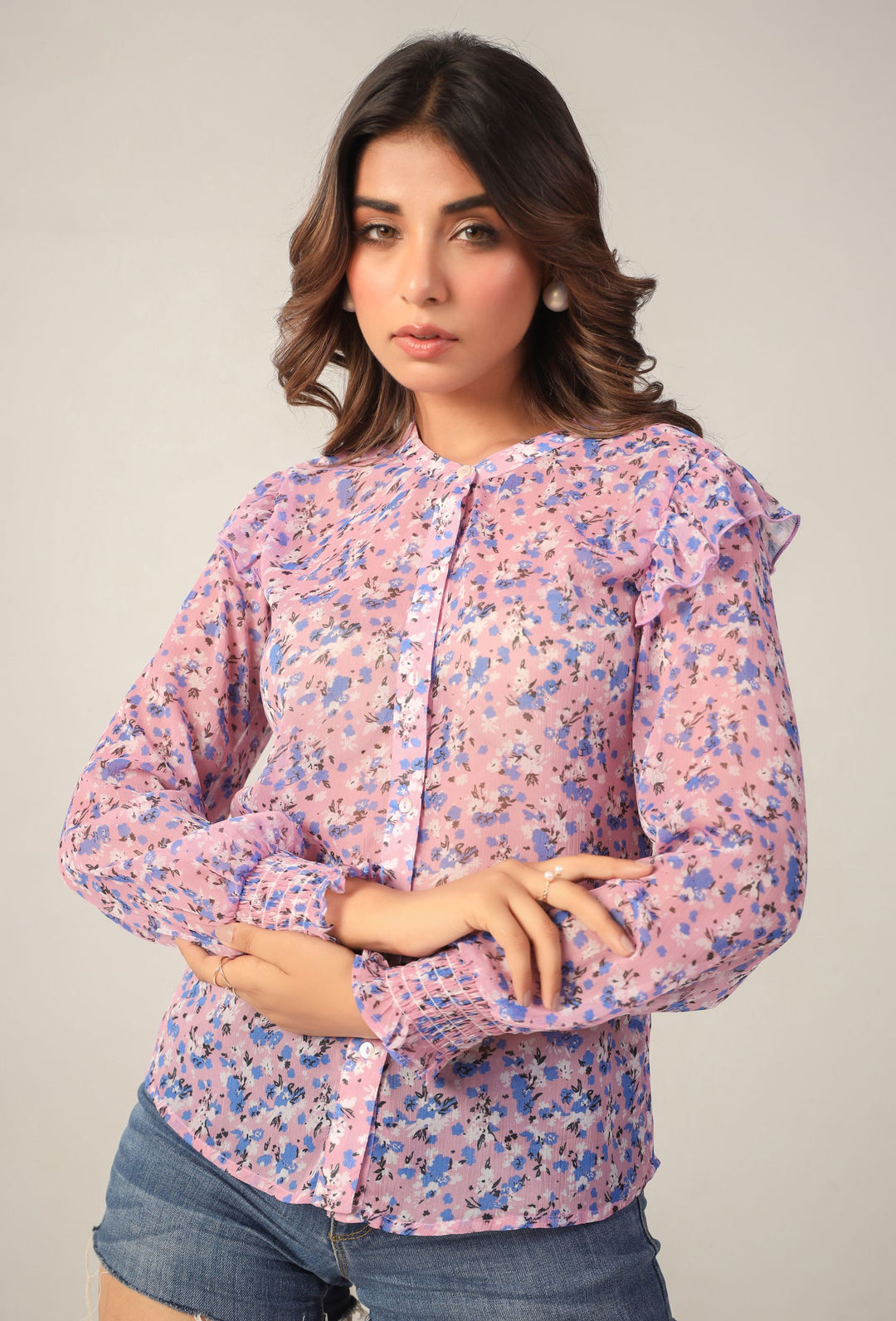 Pink floral blouse with ruffled sleeves and button front, paired with denim shorts for casual Western wear