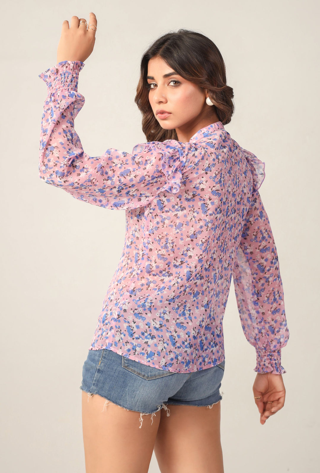 Pink floral blouse with ruffled sleeves and neckline, paired with denim shorts for Western wear style