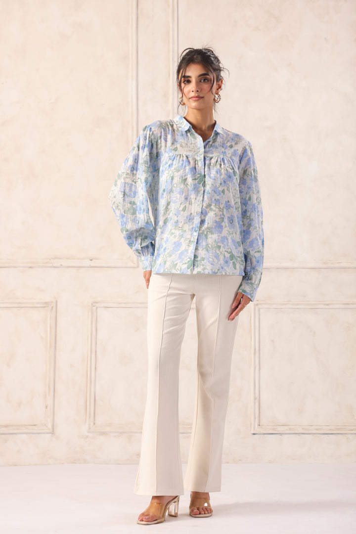 Woman in blue floral blouse with puff sleeves and cream wide-leg pants, chic Western wear outfit