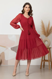Woman wearing a chic Western-style red midi dress with sheer long sleeves and tiered skirt