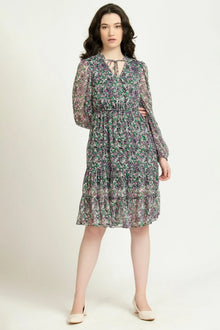 Woman wearing a long-sleeve floral print dress with ruffle skirt, standing indoors