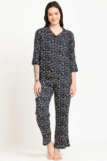 Woman wearing a floral print co-ord pajama set with three-quarter sleeves, standing barefoot.