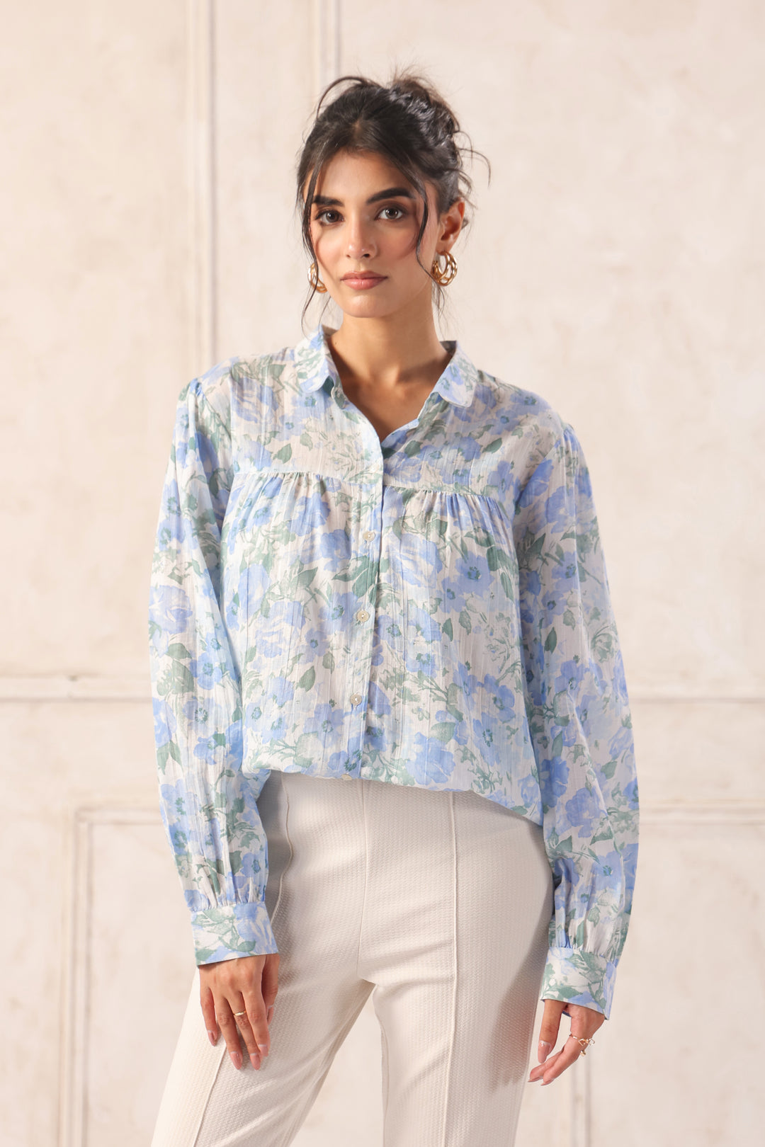 Blue floral print button-up shirt with ruffled details, paired with cream trousers for a chic Western wear look.