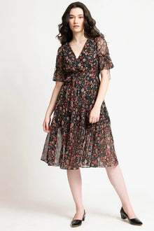 Woman wearing a black midi dress with paisley print and sheer flutter sleeves