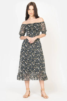 Woman wearing a black off-shoulder midi dress with floral print and sheer puff sleeves