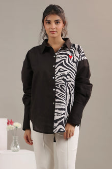 Woman wearing a black shirt with zebra animal print panel and small red heart embroidery