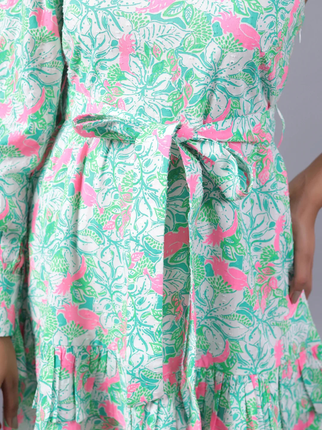 Close-up of a women's floral print dress with a green and pink belt tie detail