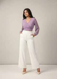 Woman wearing lavender chiffon crop top with long sleeves and white wide-leg pants