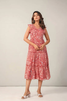 Woman wearing a red floral midi dress with ruffle sleeves and tiered skirt, standing indoors.