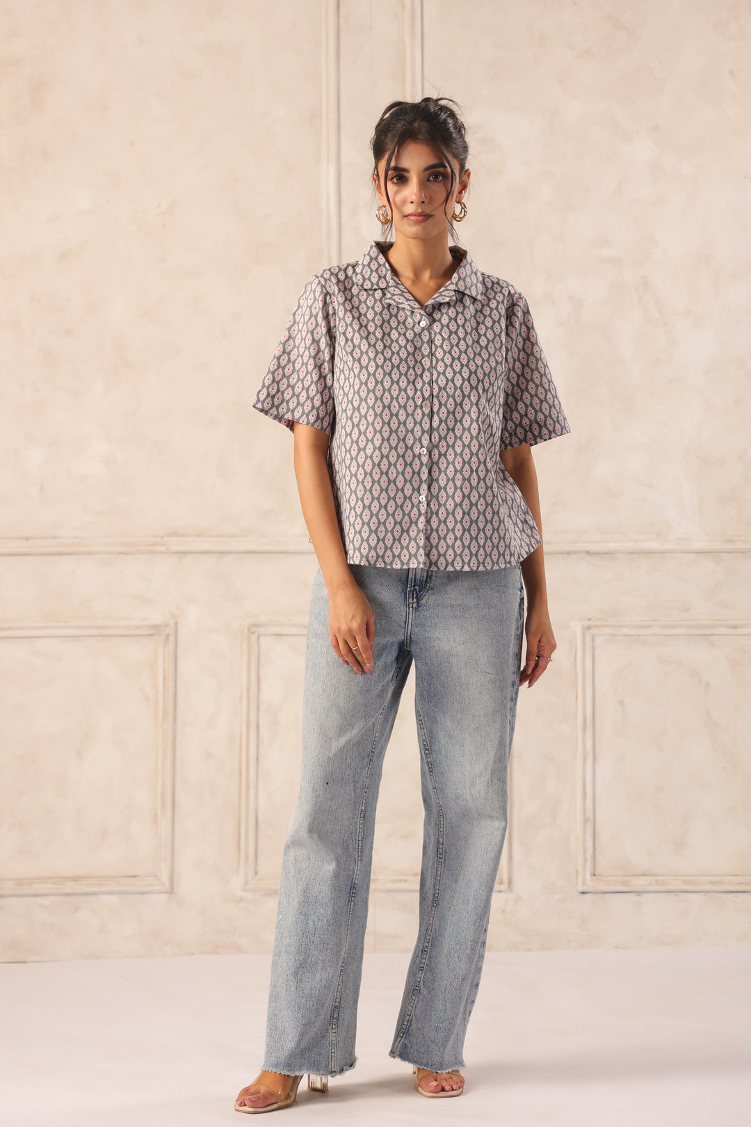 Woman modeling a patterned short-sleeve button-up shirt with wide-leg jeans, showcasing Western wear fashion.