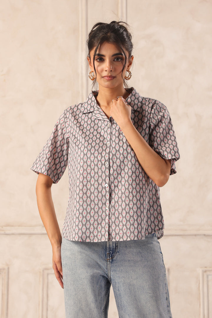 Woman wearing patterned short-sleeve shirt with geometric design, paired with light blue jeans