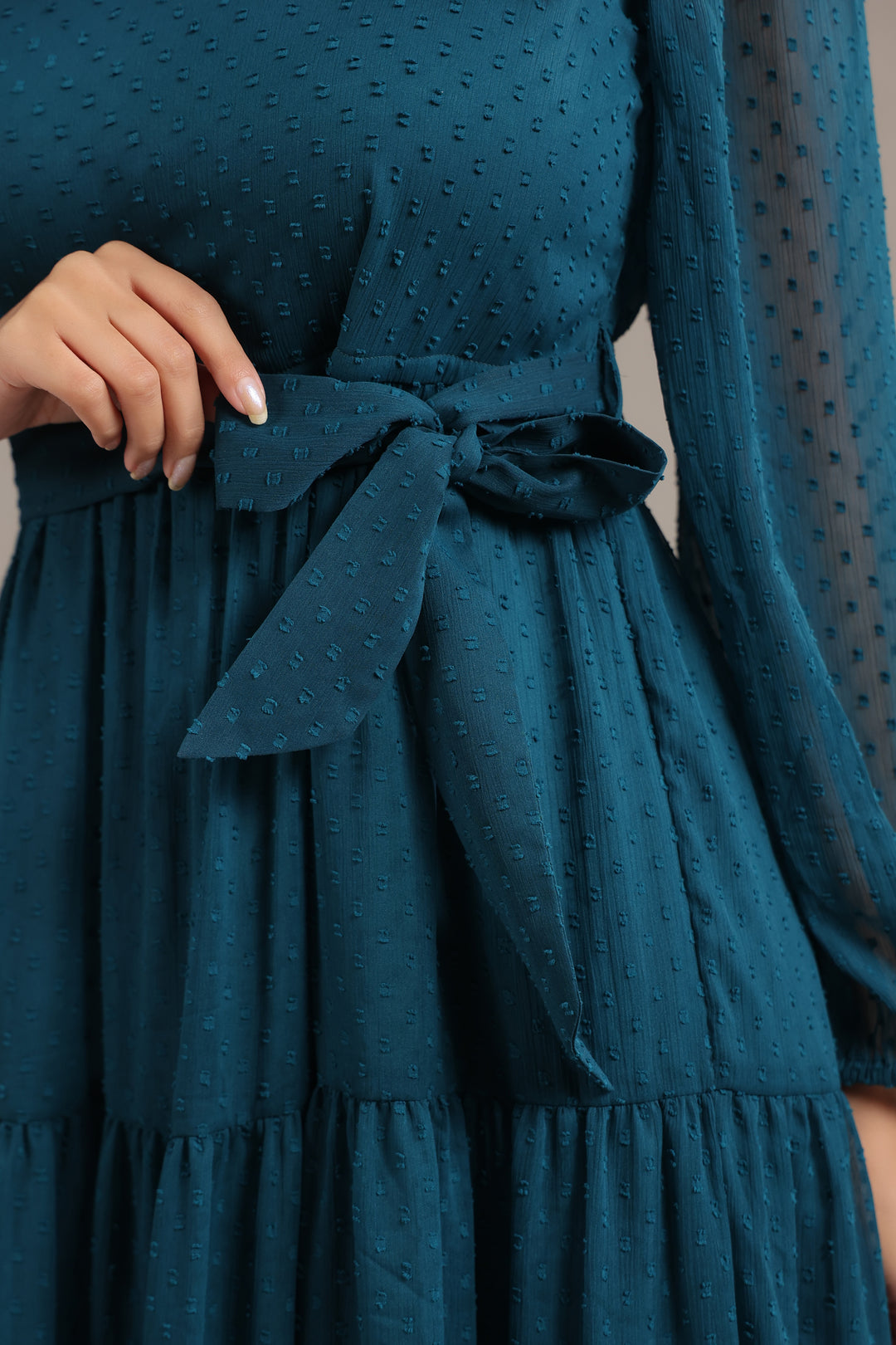 Teal dress with a bow detail on a plain background