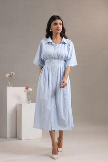 Woman in light blue striped midi dress with short sleeves and button front, neutral background
