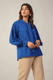 Woman in a royal blue long sleeve blouse with tie neck and beige pants, western wear fashion