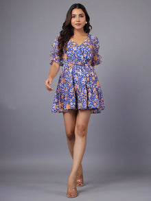 Woman in a blue and orange floral mini dress with V-neck and short sleeves, posing indoors