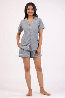 Woman wearing short sleeve button-up shirt and matching shorts co-ord set in gray print