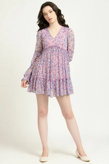 Woman wearing a long sleeve pink floral mini dress with V-neck and tiered skirt