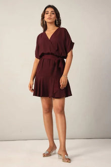 Woman wearing a maroon wrap dress with short sleeves and ruffled hem, stylish casual look