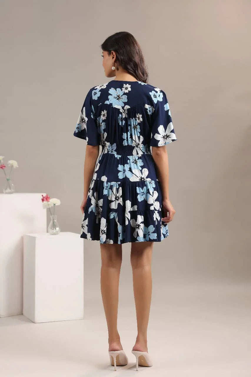 Woman wearing a navy blue floral mini dress with short sleeves, standing indoors