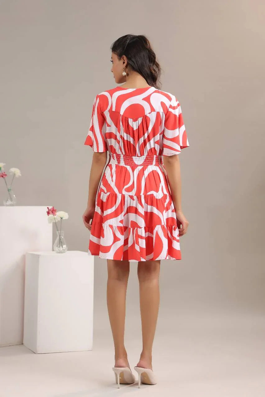 Woman in a red and white abstract print short dress with flared skirt and heels, back view