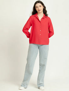 Woman wearing a bright red long sleeve shirt and light blue straight leg jeans
