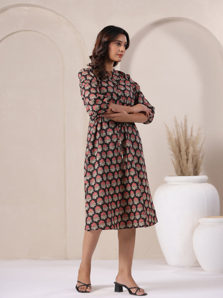 Woman wearing a black Ajrakh fit and flare cotton midi dress, showcasing flared hem.