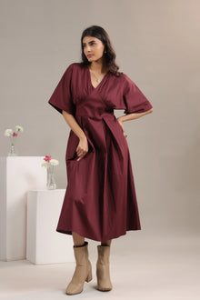 Woman wearing a wine midi dress with elbow-length sleeves and beige boots, studio background